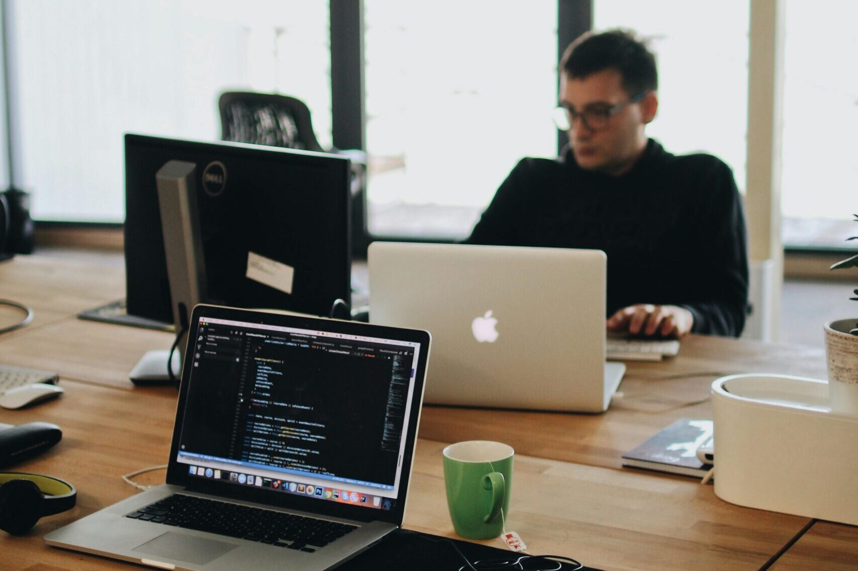 Um desenvolvedor web trabalhando em código em um ambiente de escritório moderno com vários dispositivos.