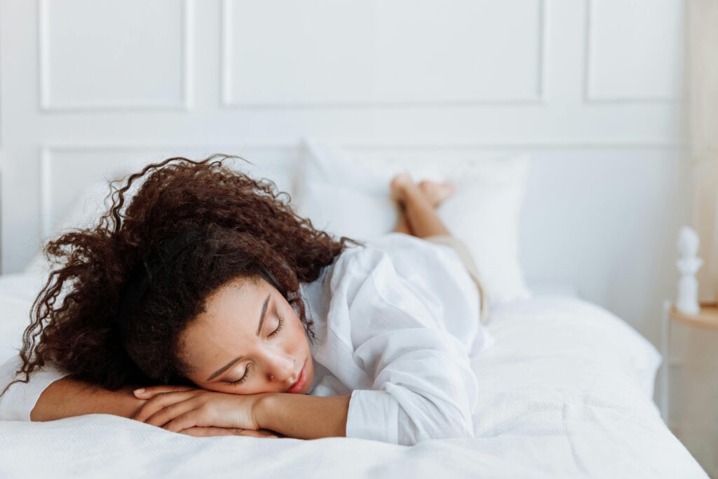 A serene image of a woman resting peacefully on a soft white bed, embodying relaxation.